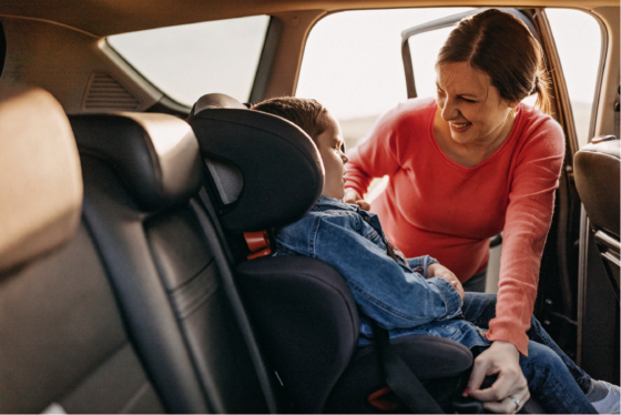 Mother putting son in car seat