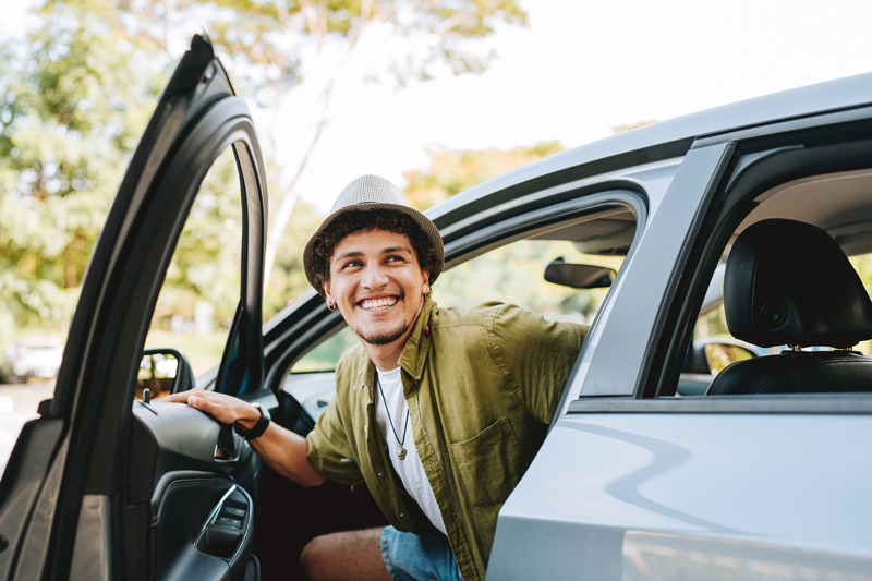 A man smiling while getting out of the front of car