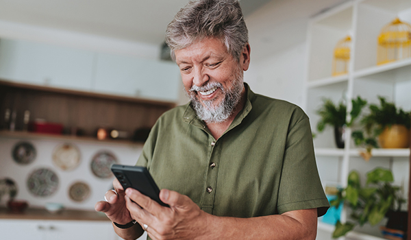 A man smiling while using his smartphone