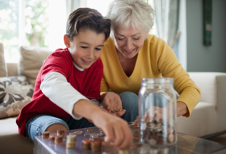A grandmother and grandchild counting coins from a jar
