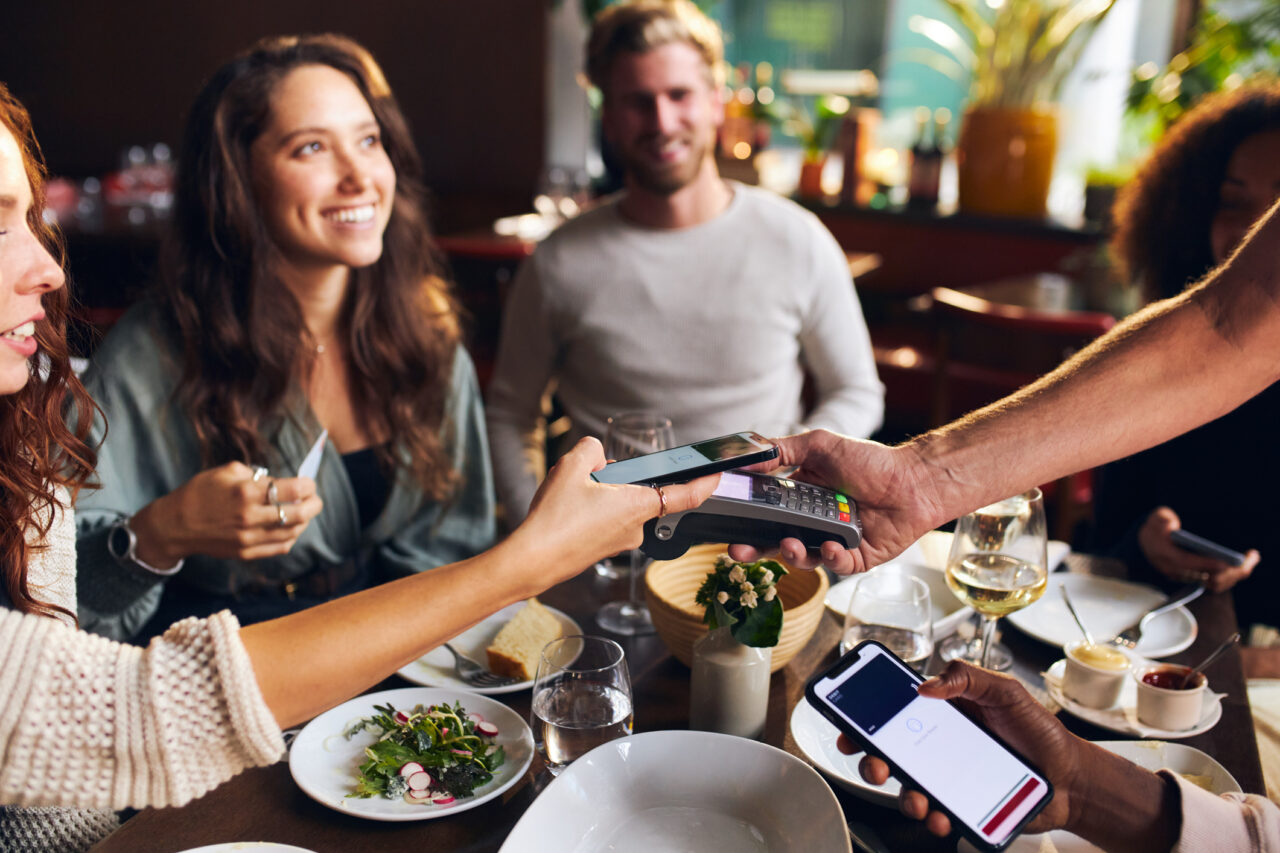A group of friends smiling while paying for the check at a restaurant