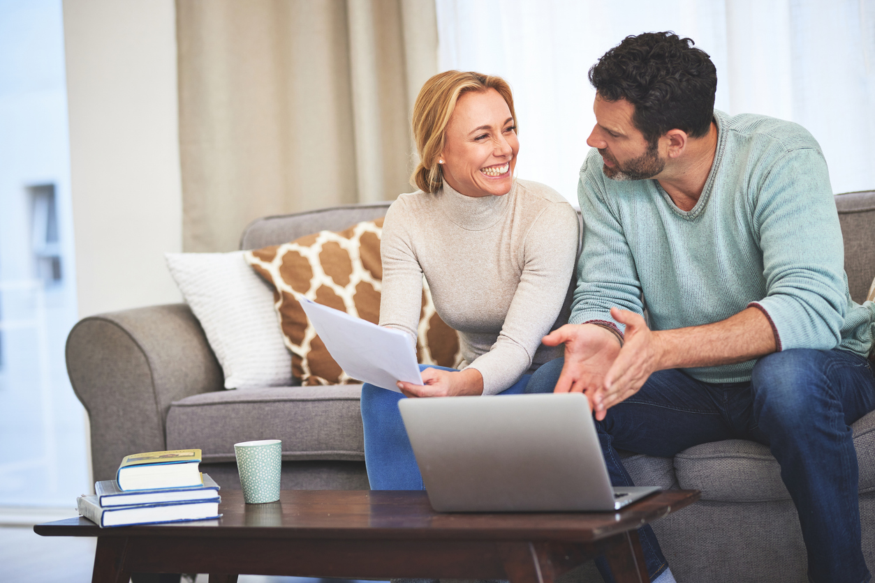 Laptop, couple and paperwork for finance in home living room on sofa for budget, taxes or savings. Computer, happiness and man and woman with documents for financial planning, expenses and bills.