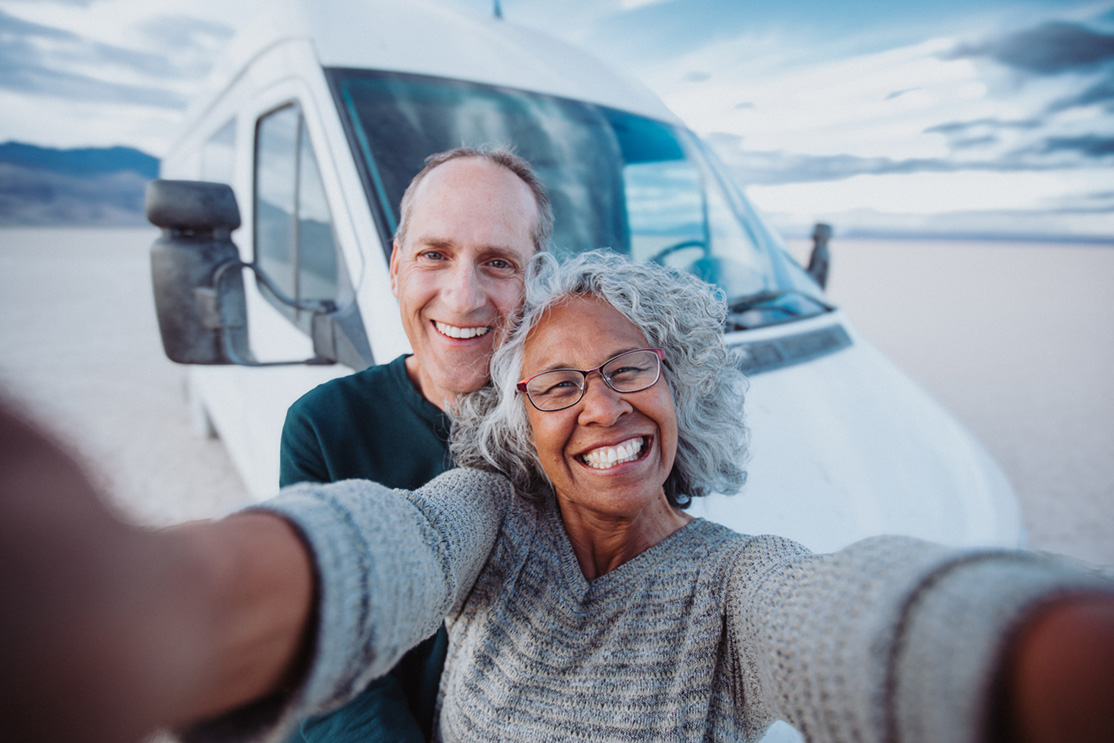 Elderly couple taking a selfie in front of an RV