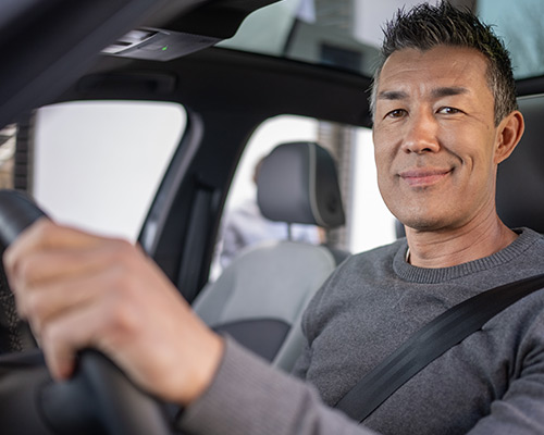 Man smiling while driving a car.