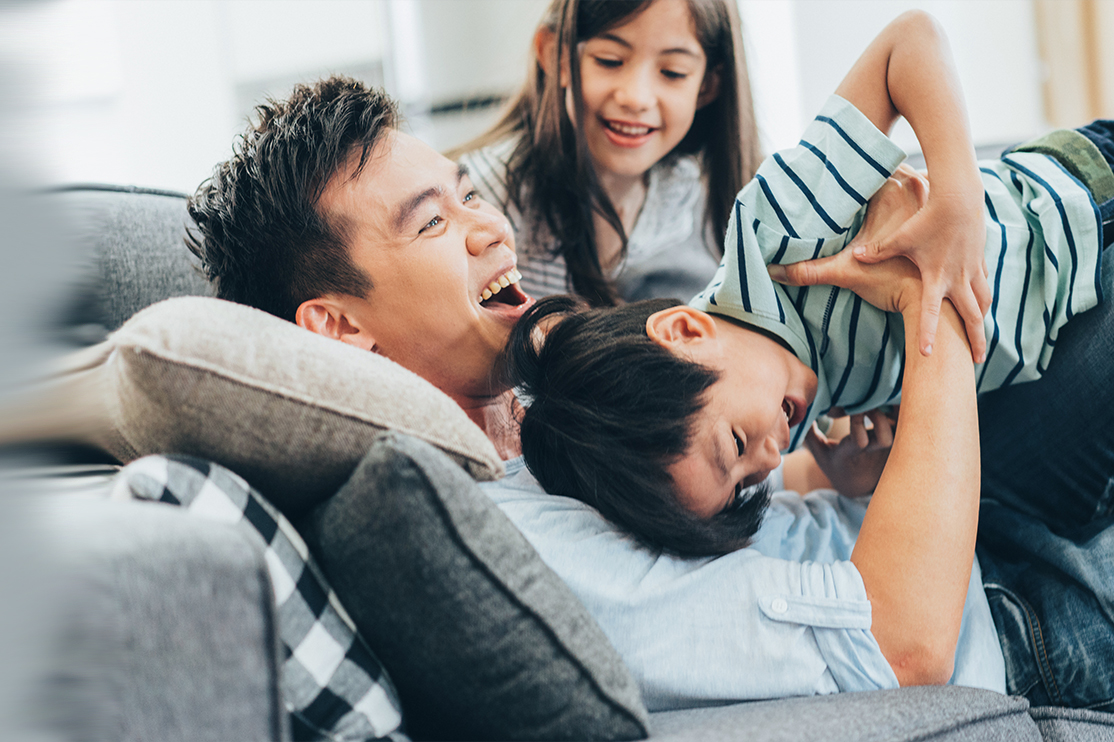 Father playing with kids on couch