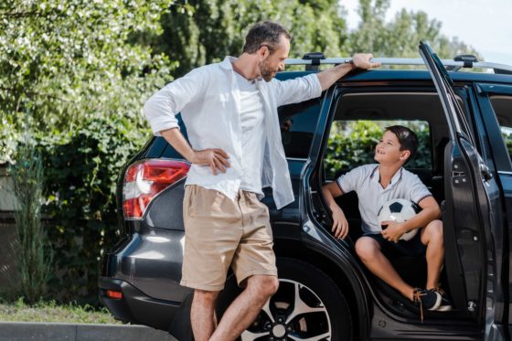 Father and son at car with soccer ball