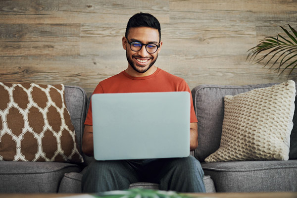 Man sitting on couch using a laptop computer.