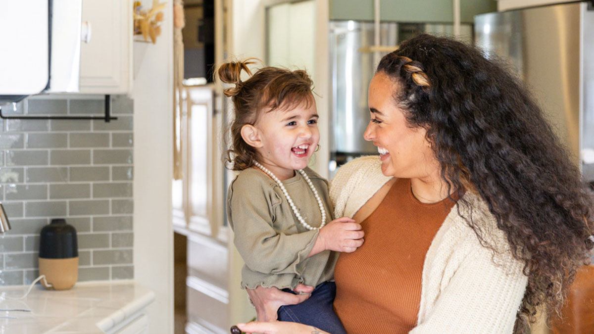 Woman holding child and smiling.