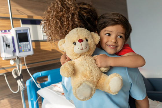 smiling boy in hospital holding teddy bear