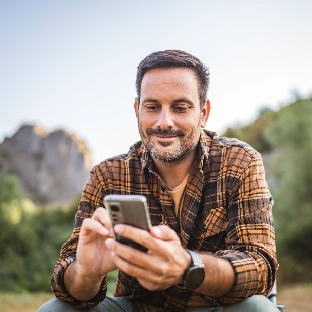 Photograph of a man outdoors on his smartphone.