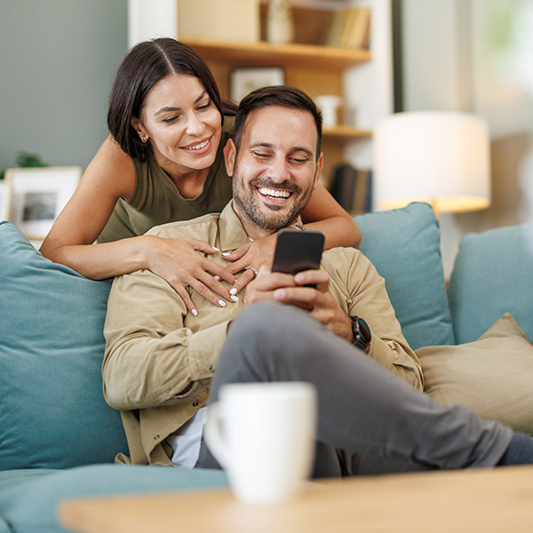 Couple smiling and looking at phone.