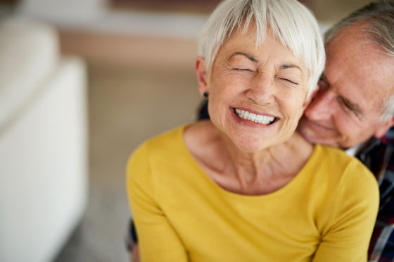 mature grinning woman with eyes closed in yellow