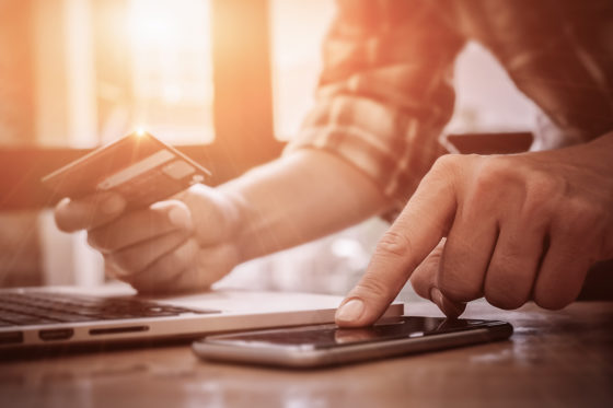 close up of man using phone and holding credit card
