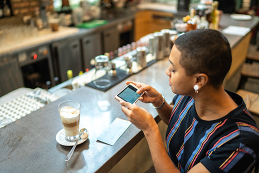 Young woman depositing check by phone in the cafe
