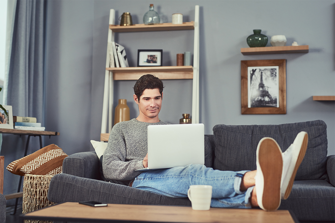 man sitting on couch using laptop