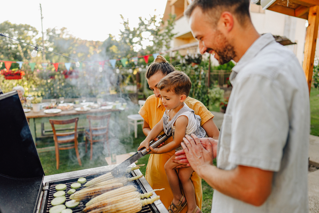 Photo of young family having a barbecue party in their backyard