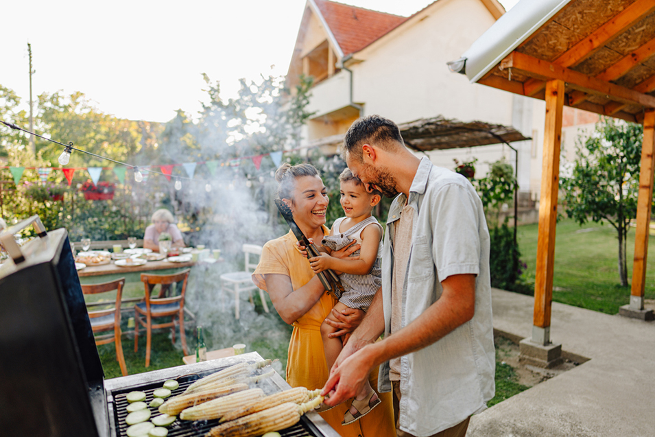 Photo of young family having a barbecue party in their backyard
