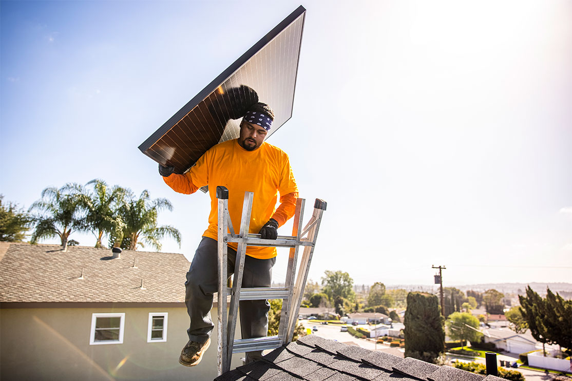 man putting a solar panel on a roof