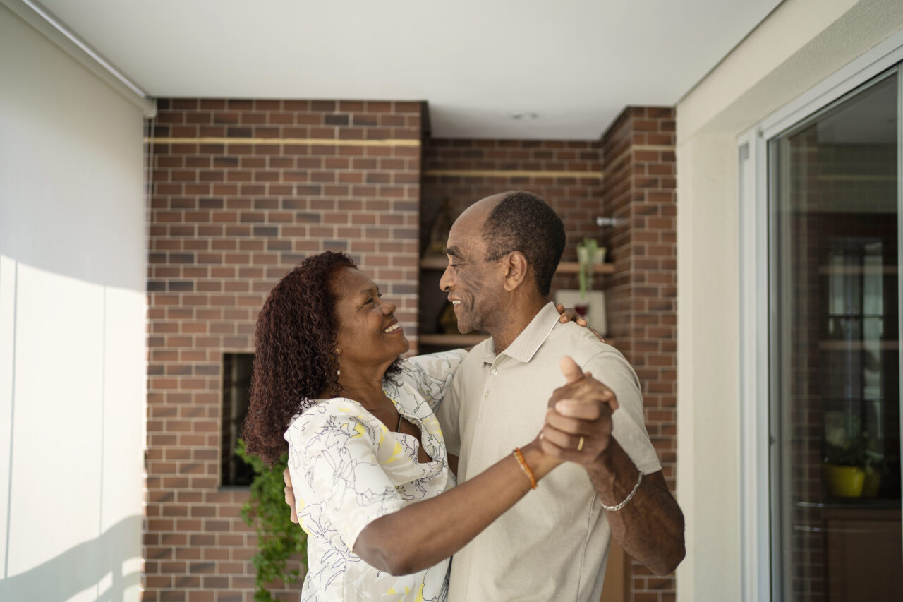 African American senior couple dancing on the balcony