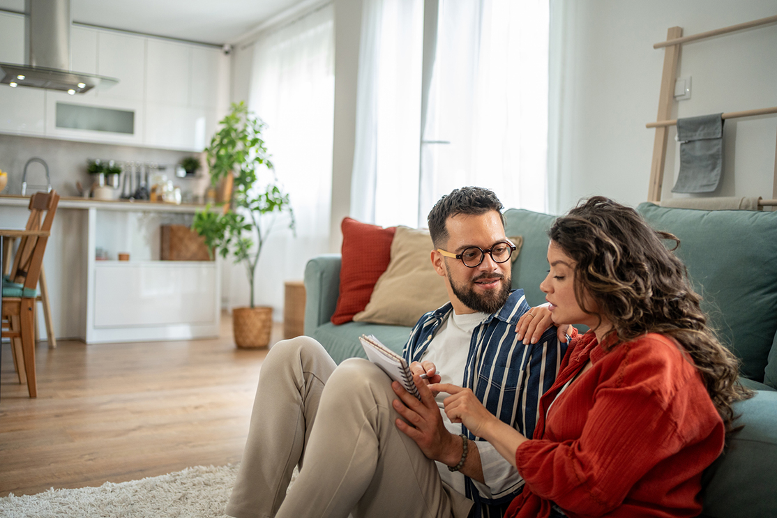 Young couple sitting on living room floor and planning their finances
