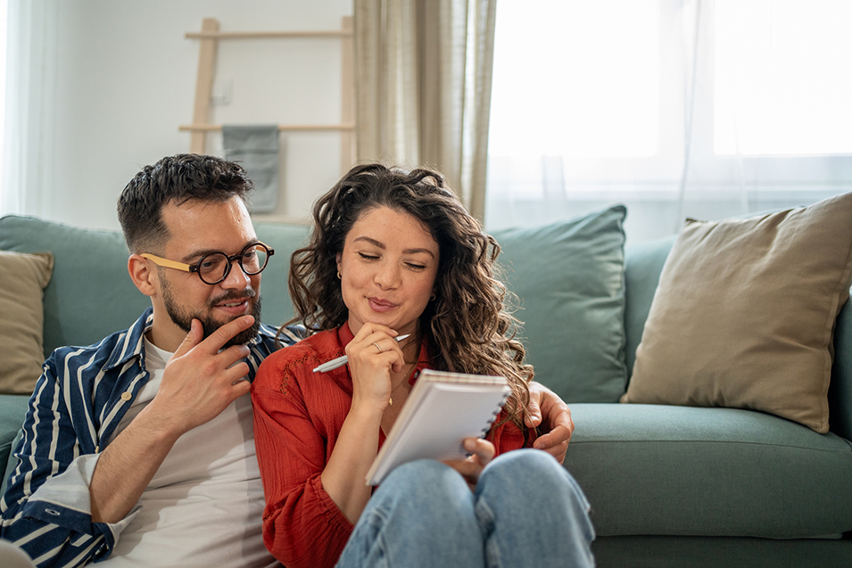 Young couple sitting on living room floor and planning their finances