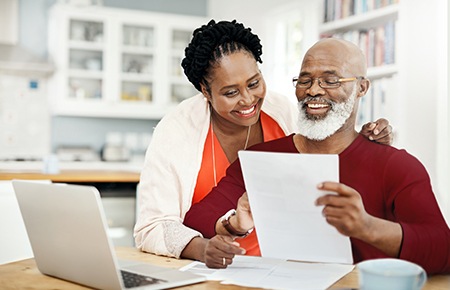 Couple in front of computer smiling at paper